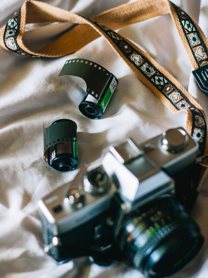 Close-up of a vintage film camera and rolls on fabric, capturing nostalgic photography.